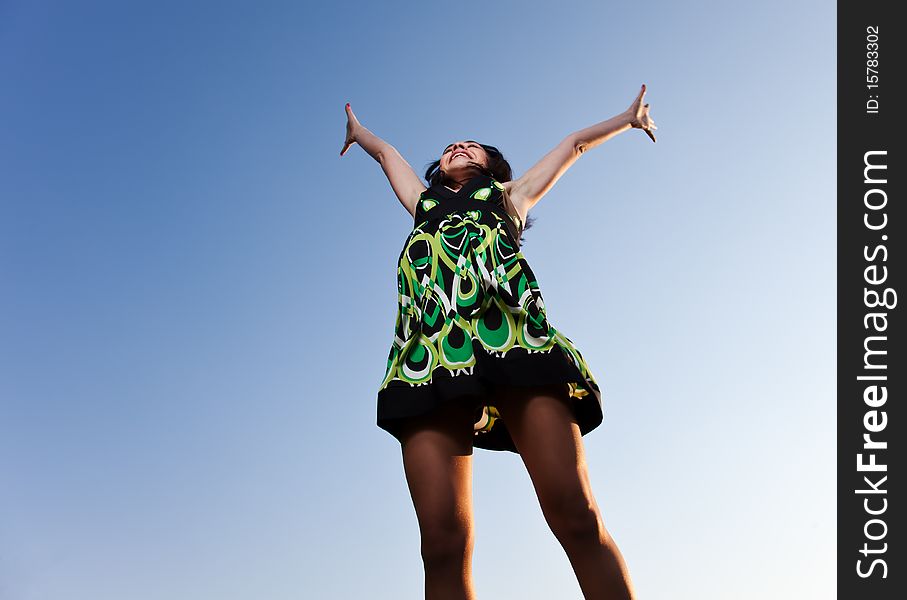 The girl in a green dress springs upwards against the dark blue sky. The girl in a green dress springs upwards against the dark blue sky