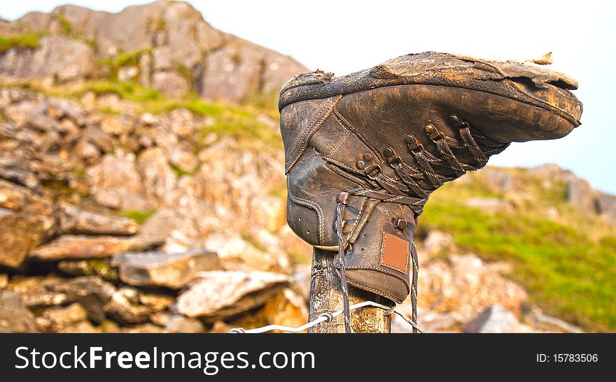 An old worn out boot discarded and retired on mountain post. An old worn out boot discarded and retired on mountain post