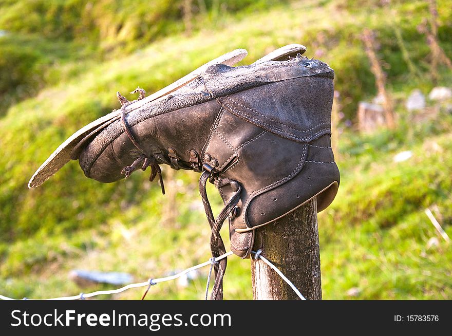 An old worn out boot discarded and retired on mountain post. An old worn out boot discarded and retired on mountain post