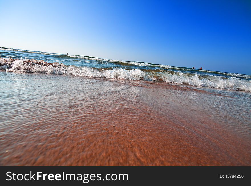 Seashore with waves and foam and blue sky