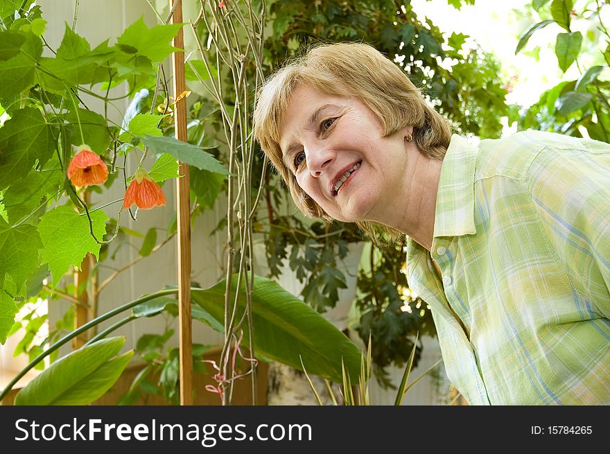 An elderly woman  in a winter garden looks at a flower with a delight