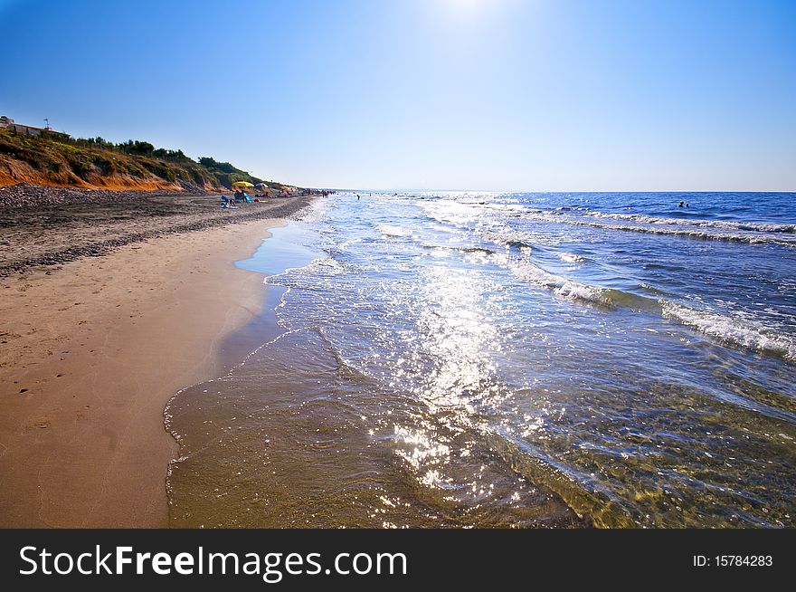 Seashore with waves and foam and blue sky