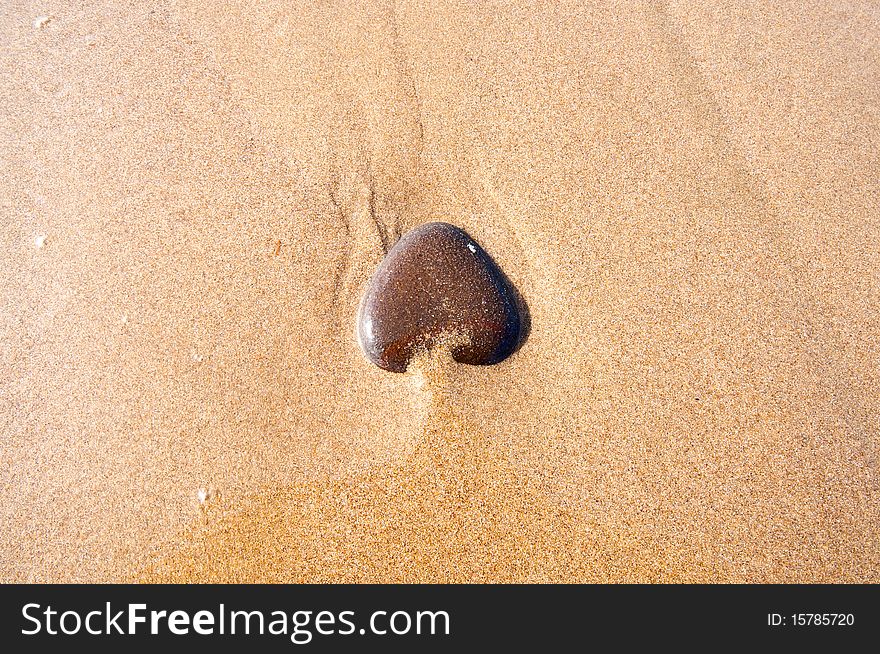 Heart-shaped stone on the sand on the seashore. Heart-shaped stone on the sand on the seashore