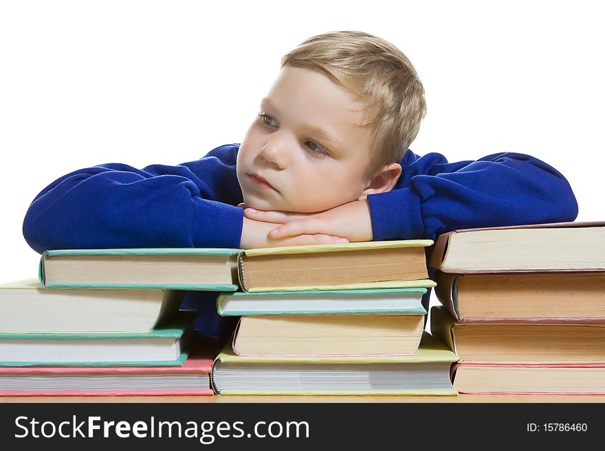 Young boy sitting at the desk with hands on top of books. Young boy sitting at the desk with hands on top of books