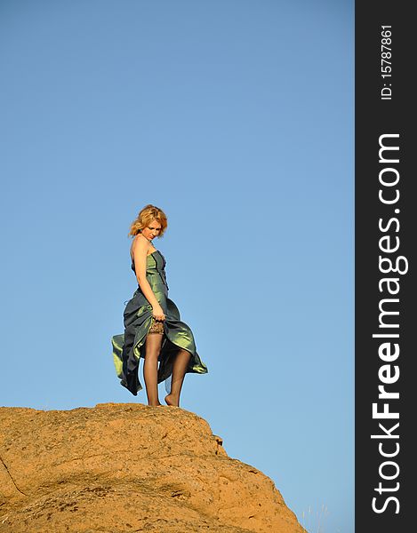 Attractive woman standing on an edge of rock and feeling sad. Attractive woman standing on an edge of rock and feeling sad