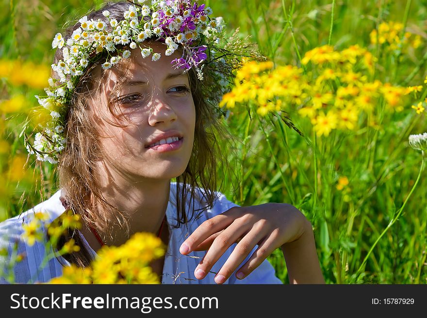 Russian girl in a wreath from camomiles is in a wheaten field