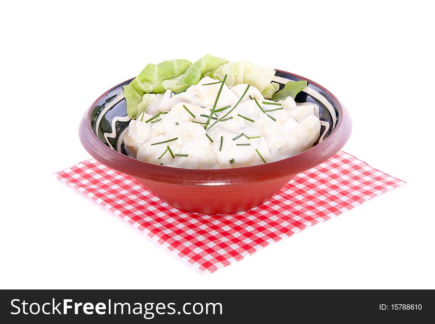 Fresh potato salad in a ceramic dish on a checkered napkin isolated over white