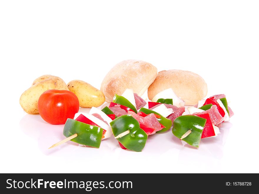 Barbecue meat skewers decorated with vegetables and bread isolated over white. Barbecue meat skewers decorated with vegetables and bread isolated over white