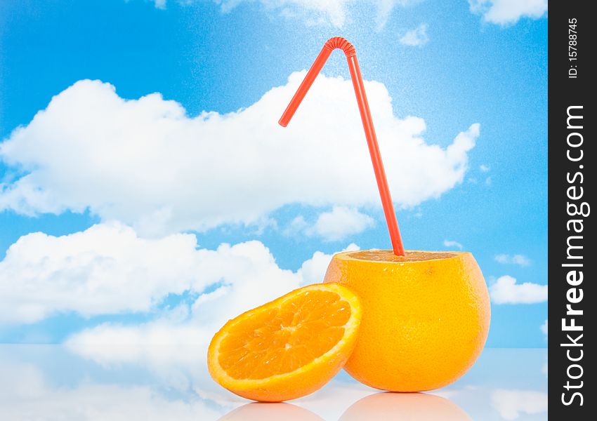 An orange with a straw against a blue cloudy sky