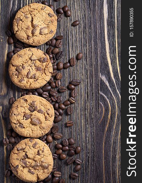 Chocolate chip cookies and coffee beans on old wooden table, top view with copy space. Chocolate chip cookies and coffee beans on old wooden table, top view with copy space