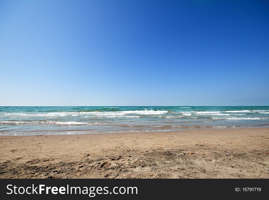 Seashore with waves and foam and blue sky