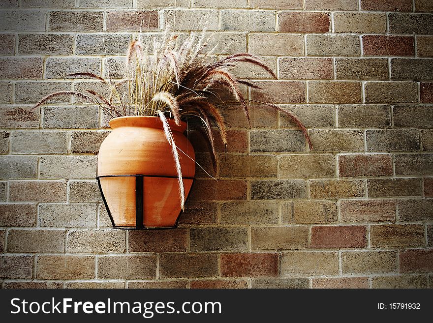 Old grass pot on brick wall