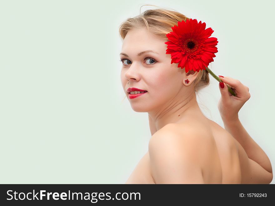 Portrait of the young beautiful girl holding a red flower at itself on a head. Portrait of the young beautiful girl holding a red flower at itself on a head