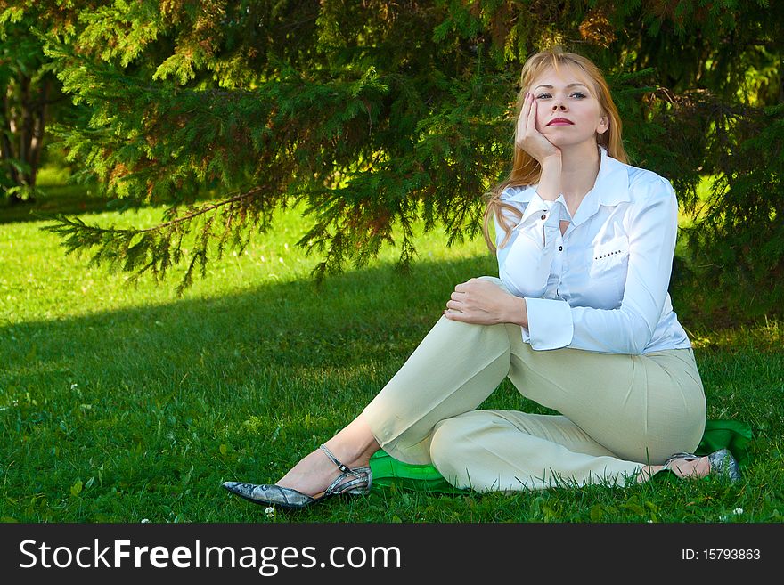 Attractive girl in white clothes misses on a green lawn. Attractive girl in white clothes misses on a green lawn