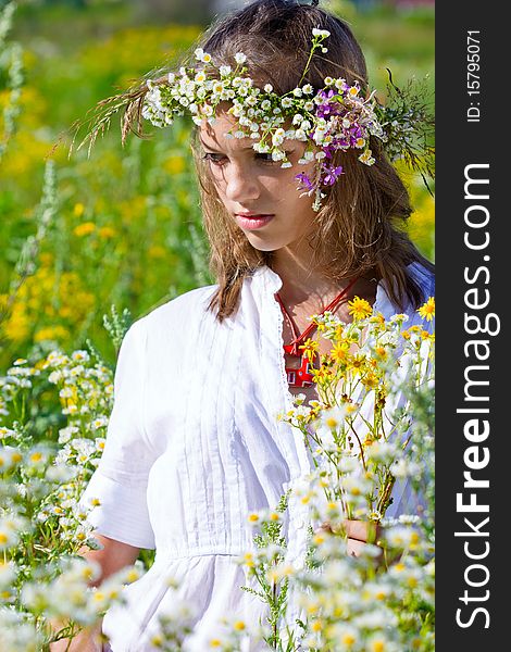 Russian girl in a flower field and a wreath on a head