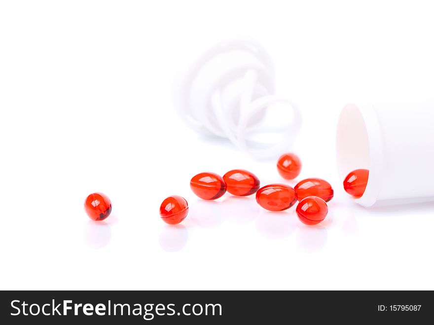 Red tablets scattered from the bottle isolated over white background. Red tablets scattered from the bottle isolated over white background