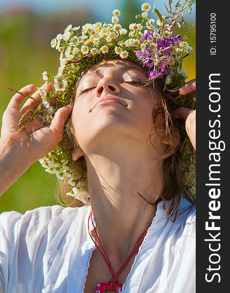 Russian girl in a flower field and a wreath on a head