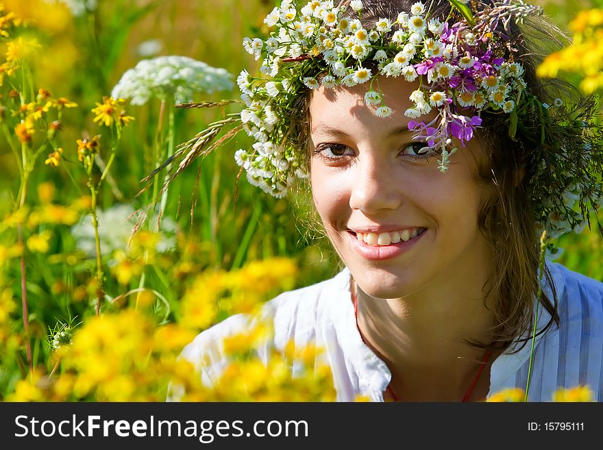 Russian girl in a flower field and a wreath on a head