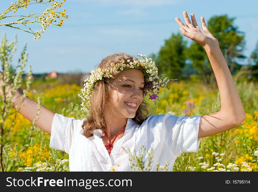 Russian girl in a flower field and a wreath on a head