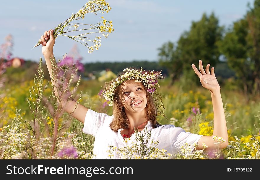 Russian girl in a flower field and a wreath on a head