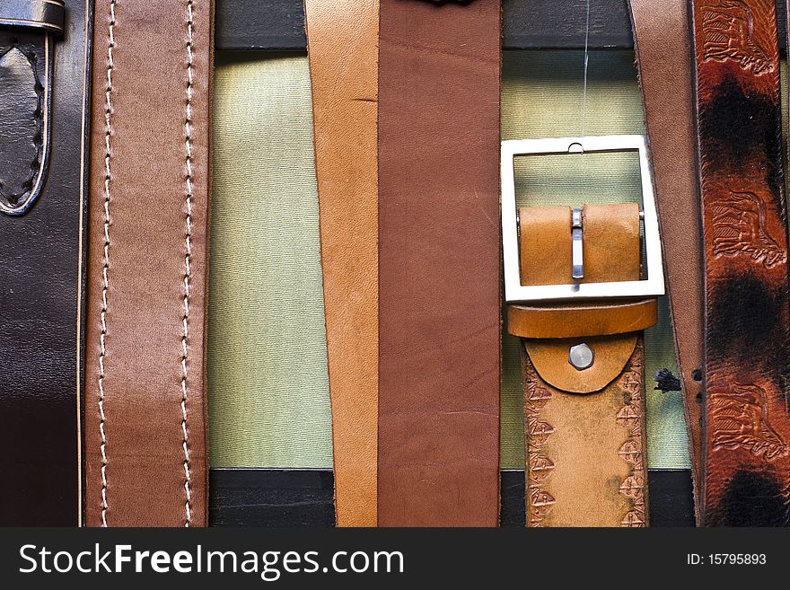 Series of leather belts create a vertical fashion background.