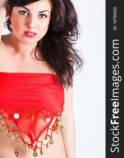 Beautiful young woman in red oriental shawl covering her top with naked belly, belly dancer