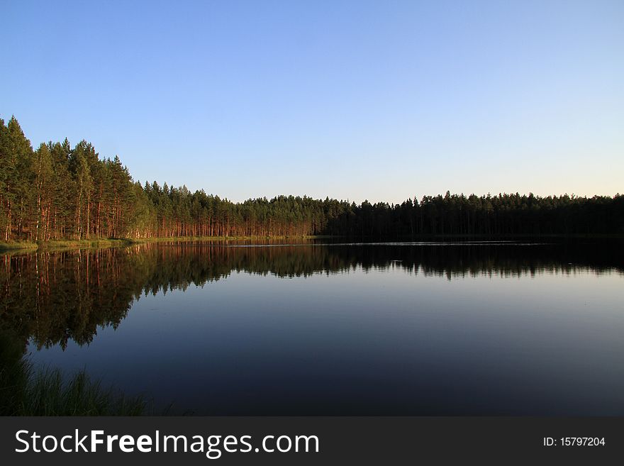 Beautiful Russian deep lake. Summer day. Clearly.The pines are reflected in the water.