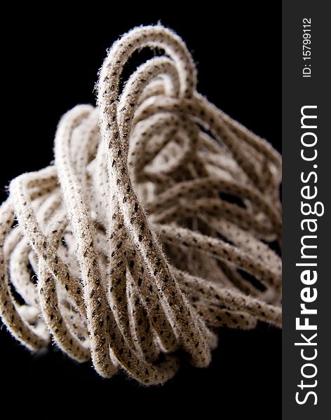 Photo of hank of rope closeup on a black background. Focus on the foreground