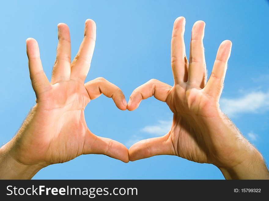 Photos of male hands, folded in the shape of the heart, against the blue sky. Photos of male hands, folded in the shape of the heart, against the blue sky