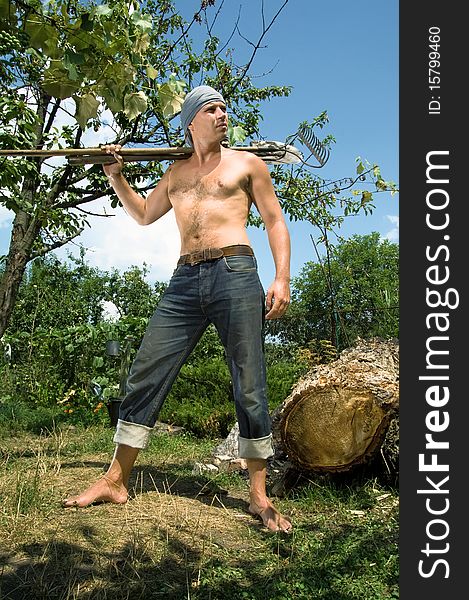 Photo of a young man with a spade and rake on the background of nature. Photos made with the use of special effects.