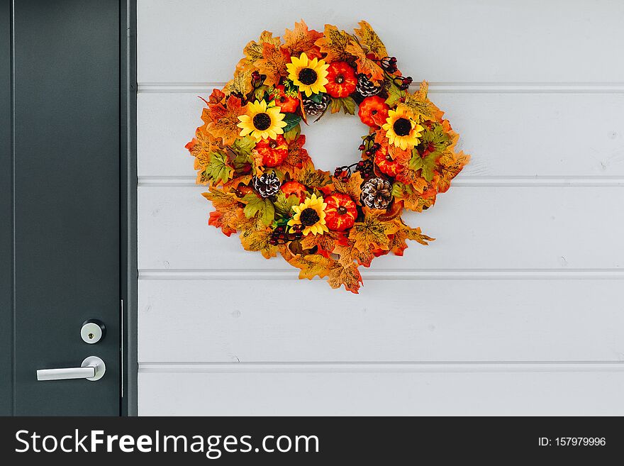Autumn wreath with sunflowers, pumpkins and maple leaves on front door