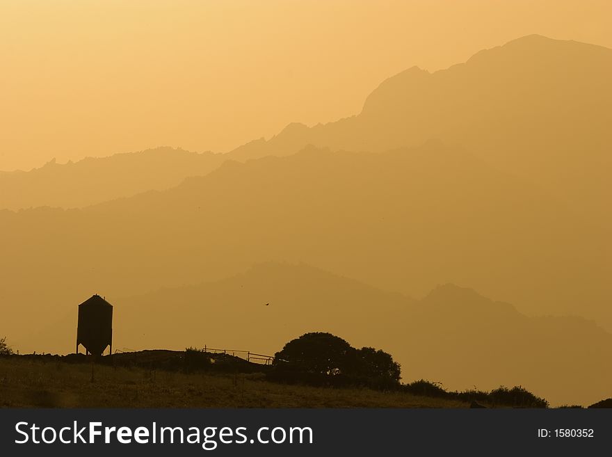 Grain Silo with the silhouette of the mountains in the backgrouns. A serene landscape. Grain Silo with the silhouette of the mountains in the backgrouns. A serene landscape