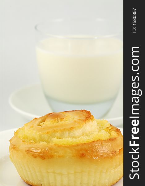 Sweet Bun on White Plate and Glass of Milk. Shallow DOF. Sweet Bun on White Plate and Glass of Milk. Shallow DOF.