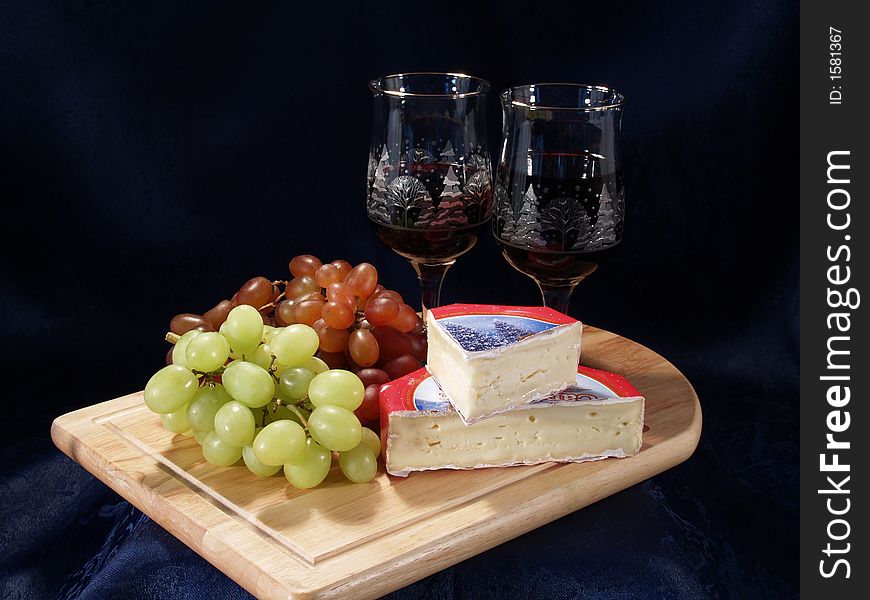 Wine and Cheese dislpayed on a cutting board with some grapes. Wine and Cheese dislpayed on a cutting board with some grapes.