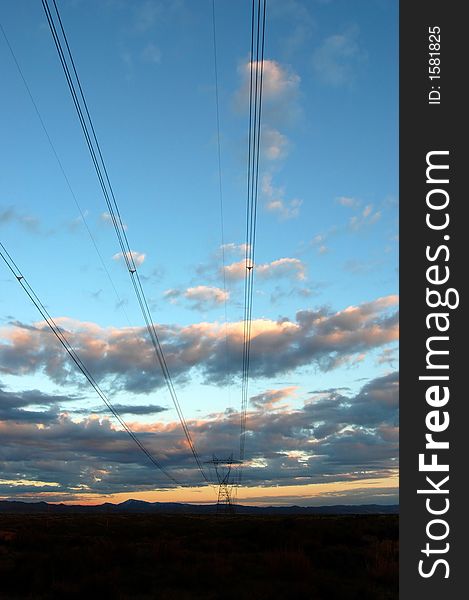 View of powerlines with sunset and clouds in background. View of powerlines with sunset and clouds in background