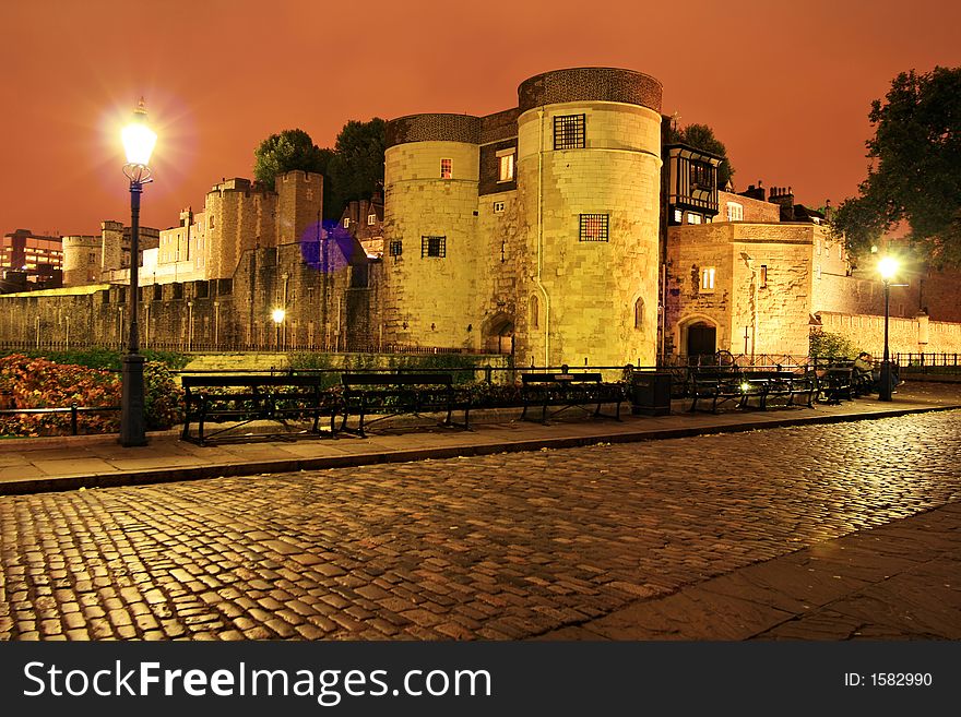 The Tower of London at night with a man sitting on a bench, UK