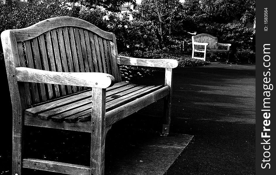 Wooden park benches along cement walking path in black and white