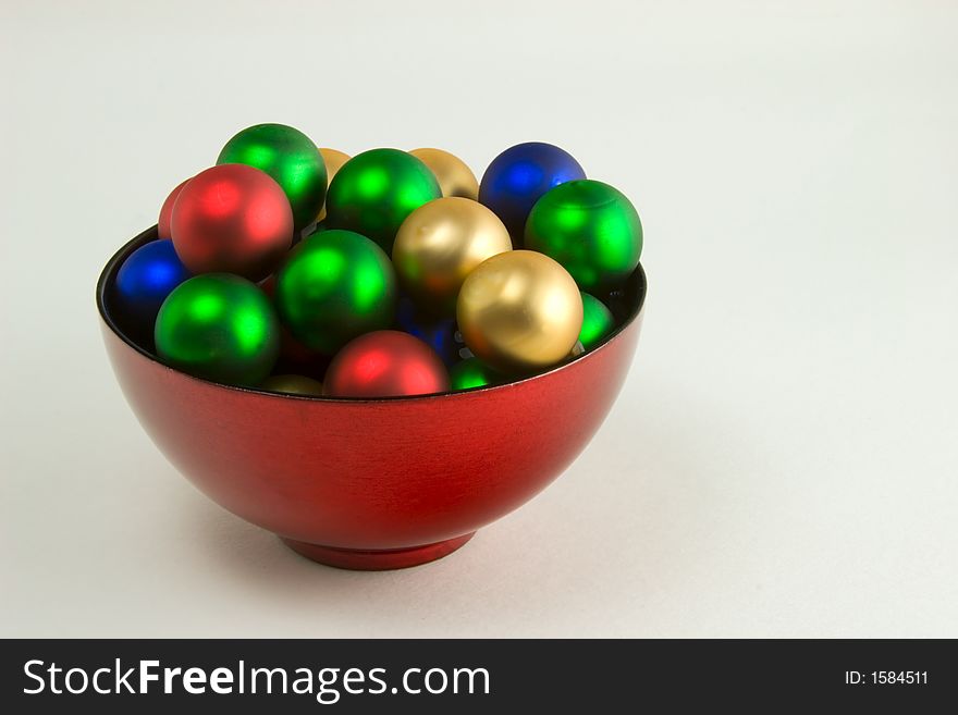 A red bowl filled with Christmas ornaments. A red bowl filled with Christmas ornaments