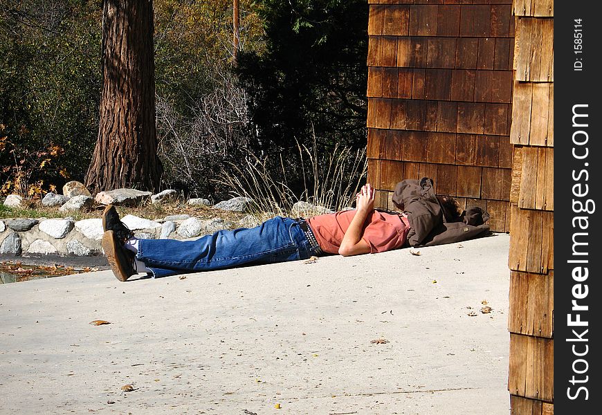 Person laying out in the sun with a coat over their head. Person laying out in the sun with a coat over their head