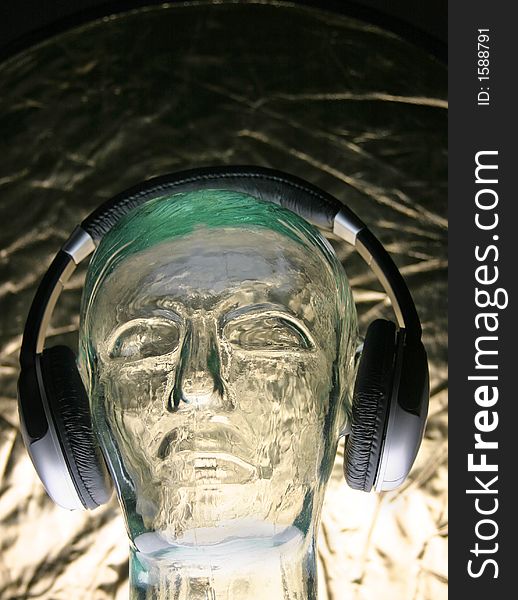 Front view of headphones on glass head on gold. Front view of headphones on glass head on gold