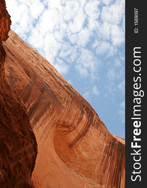 Water patterns in the face of a sandstone wall contrasting with light clouds in the sky. Lake Powell, Utah. Water patterns in the face of a sandstone wall contrasting with light clouds in the sky. Lake Powell, Utah.