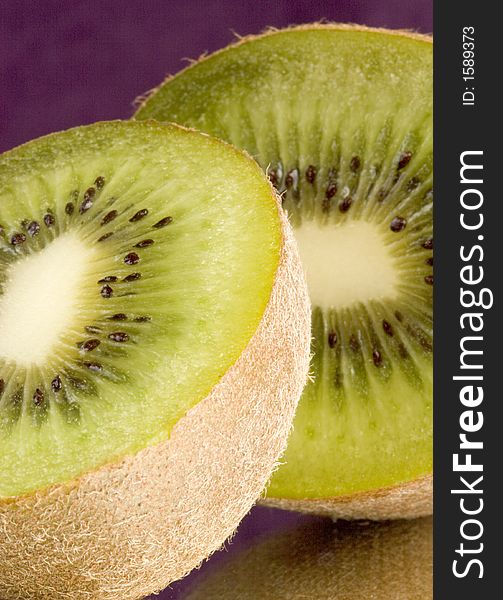 Macro of two halves of a kiwi with a purple background on mirror. Macro of two halves of a kiwi with a purple background on mirror