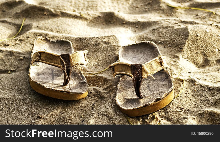 Pair of slippers laying on the sand. Pair of slippers laying on the sand