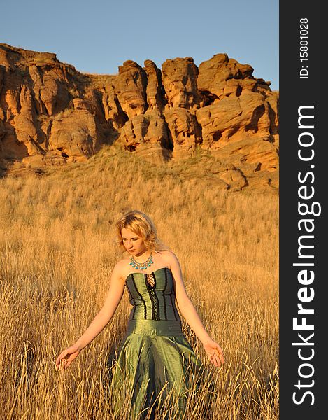 Attractive woman in a long green dress walking by steppe. Attractive woman in a long green dress walking by steppe