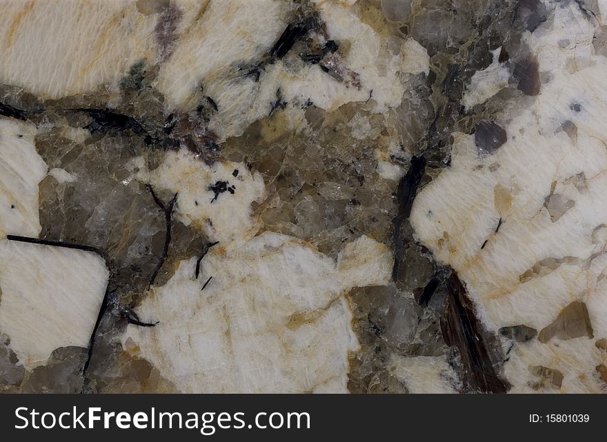 Surface of the stone. Granite. Pale yellow and reddish-brown shades. Mottled pattern.