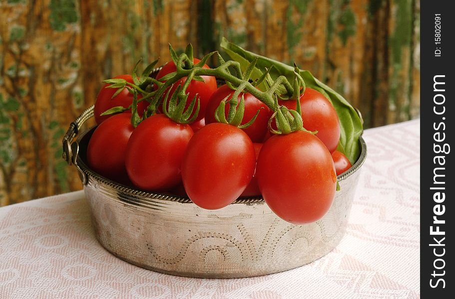 Fresh cherry tomatoes in old iron bowl on wooden background