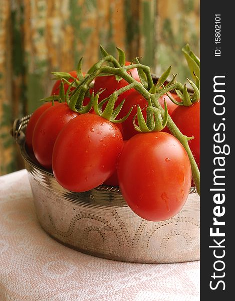Fresh cherry tomatoes in old iron bowl on wooden background