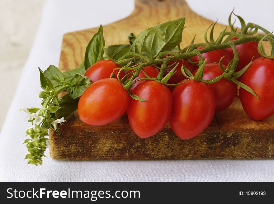 Fresh cherry tomatoes and fresh basil on wooden tray