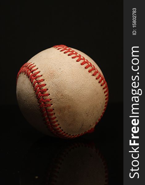 Closeup of a baseball against a black background.