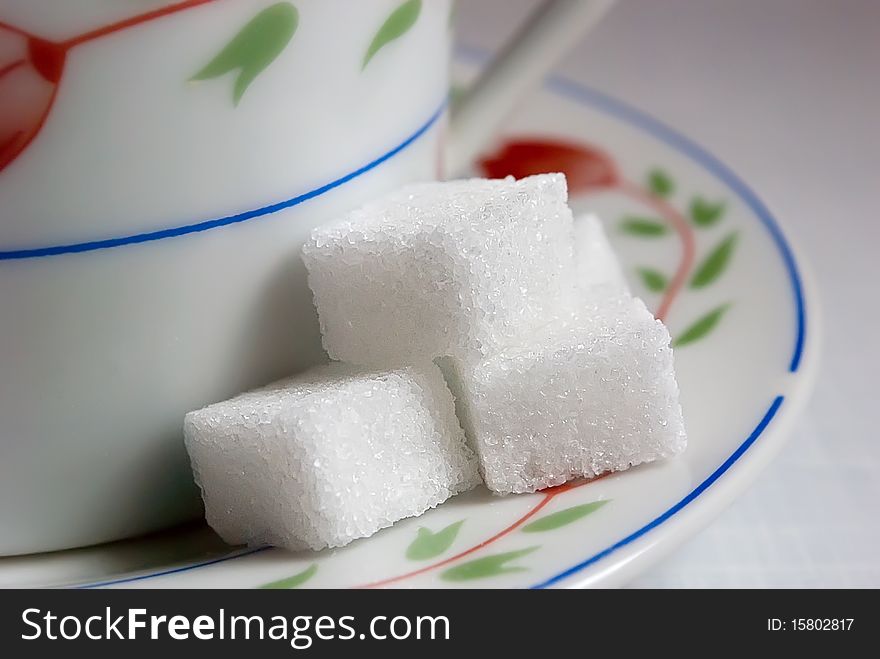 Slices of white sugar lump sugar on a saucer with a cup. Slices of white sugar lump sugar on a saucer with a cup.